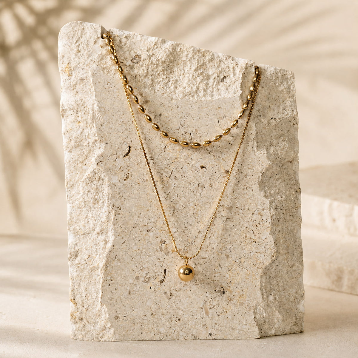 Goudkleurige layered ketting Indigo Necklace van hi SISU op travertin steen