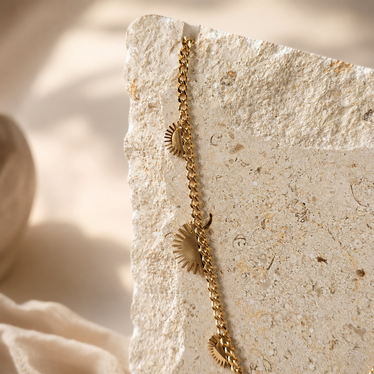 Gouden chain ketting met zonhangers op travertin steen, close-up