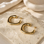 Gouden chunky hoops Blair Earrings met zachte hoekige vorm, op travertin steen bij hi SISU