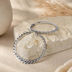 Grote zilveren oorringen met gedraaid design, Chloe Earrings van hi SISU tegen travertin steen