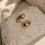 Druppelvormige gouden oorbellen met glanzende finish in daglicht
