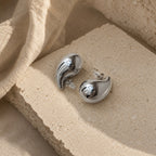 Zilveren druppel oorbellen Isabel Earrings van hi SISU, close-up op travertin steen